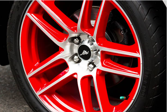 A black tire rim with a red stripe behind the wheel spokes.