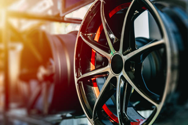 A car wheel with a bright red rim and silver bolts in the center